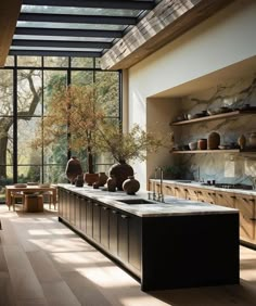 a large kitchen with lots of counter space and vases on the counters in front of windows