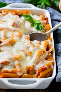 a casserole dish with meat, cheese and sauce in it on a wooden table