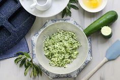 a bowl filled with shredded green vegetables next to other dishes and utensils on a table