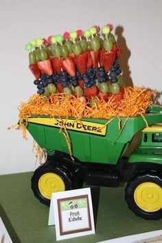 a green toy truck filled with grapes and strawberries