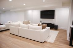 a living room filled with white furniture and a flat screen tv mounted on the wall