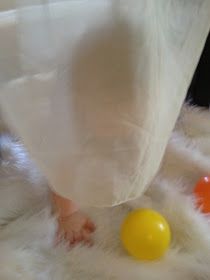 a baby is playing with an orange and yellow ball on the fur covered floor,