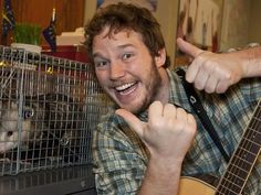 a man holding a guitar in front of a rat cage