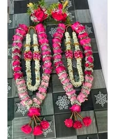 two pink and white garlands with flowers on them sitting on a checkered tile floor