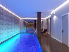 an indoor swimming pool with blue lights and water features in the center, along with two lounge chairs on either side