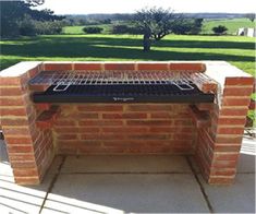 an outdoor bbq grill sitting on top of a cement slab next to a park