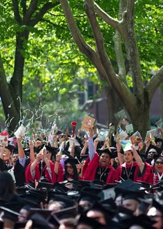 graduates in caps and gowns throw confetti into the air