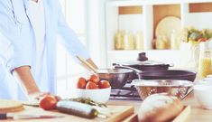 a woman is preparing food on the counter in her kitchen with pots and pans