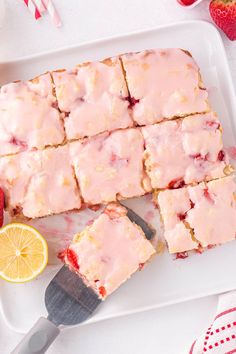 strawberry shortbreads with icing and strawberries on a white plate next to a knife