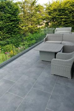 an outdoor patio with grey tiles and wicker furniture