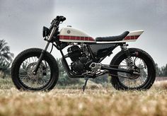 a motorcycle is parked in the grass on a cloudy day