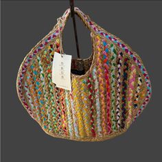 a multicolored handbag hanging on a wooden hanger with a price tag