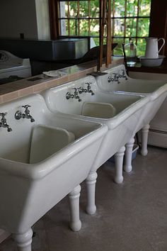 a row of white sinks sitting next to each other on top of a kitchen counter