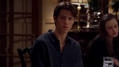 a young man and woman sitting next to each other at a table with drinks in front of them