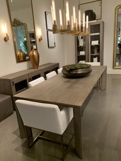 a dining room table with white chairs and a large mirror on the wall behind it