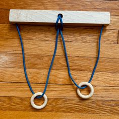 two blue and white ropes connected to a wooden block on a wood floor with a hook