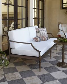 a white couch sitting on top of a checkered floor next to a glass door