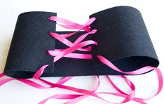 a roll of black paper with pink ribbon on it