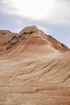 a man riding a horse on top of a dry grass covered field with mountains in the background