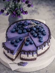 a cake with blueberries on top and purple flowers in the backgroung