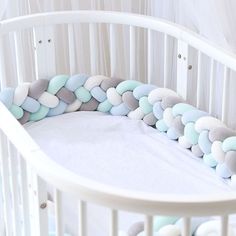 a white crib with blue, grey and white pillows on it's sides