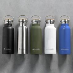 thermos are lined up in a row against a gray wall, and one is empty