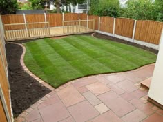 a backyard with grass and wooden fenced in areas around the area, including a brick walkway