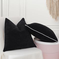 two black pillows sitting on top of a white chair