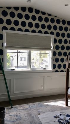 a bedroom with blue and white patterned wallpaper, window sill, and ladder