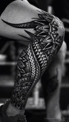 a black and white photo of a man's leg with an intricate tattoo design on it