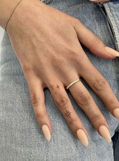 a woman's hand with a small star tattoo on her left thumb and finger