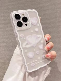 a person holding up a phone case with hearts on the front and back cover in white