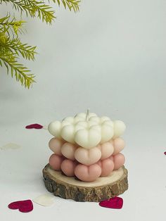 a small candle is sitting on a piece of wood with petals around it and the candles are made out of balloons