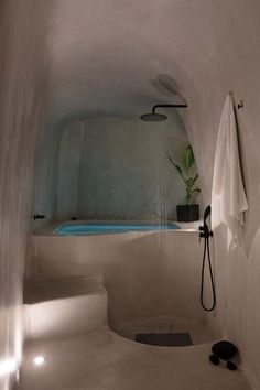 a white bathroom with a blue pool in the corner and towels hanging on the wall