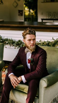 a man in a tuxedo sitting on a green chair with his legs crossed