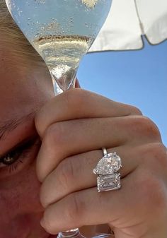 a close up of a person holding a wine glass with a diamond ring on it