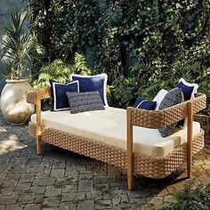 a wicker daybed with blue and white pillows sits in the middle of a brick patio