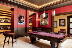 a billiard table in a room with red walls and lights hanging from the ceiling