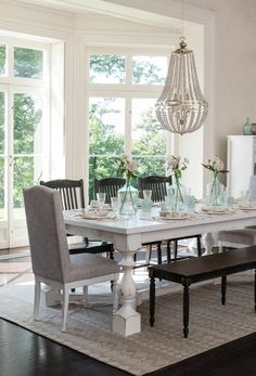 a dining room table and chairs with chandelier in the background on a rug