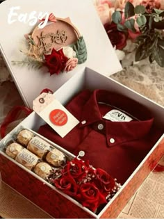 an open box with some wine and chocolates in it on a table next to flowers