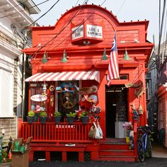 a red building with an american flag on the front porch and two bikes parked outside