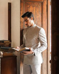 a man standing in front of a wooden door holding a book and looking at it