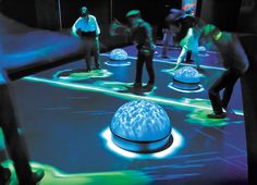 several people are playing with interactive games on the floor in a room that is lit up