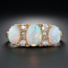 A trio of glistening opals, displaying a complete palette of bright pastel colors, alternate with a vertical row of four sparkling old-cut diamonds in this superb British three-stone ring, circa late-nineteenth century. The ring is finely crafted in rich 18 karat yellow gold and is further adorned with lovely scrolled shoulders. A many splendored beauty. 2,950.00 USD Opal And Diamond Ring, Bijoux Art Nouveau, Pretty Jewellery, Opal Jewelry, Vintage Jewellery, Opal Rings, Ring Verlobung