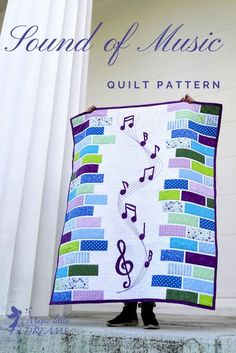 a woman holding up a quilt with musical notes on it and the words sound of music written in purple