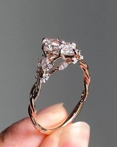 a hand holding a ring with two diamonds on it's sides and the center stone in