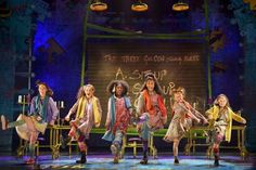 the cast of hairstylist performs on stage in front of a chalkboard