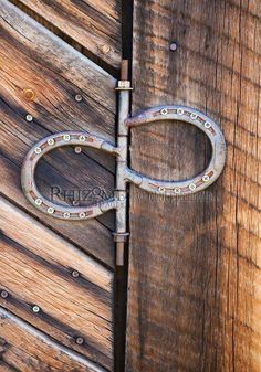 an old pair of scissors is on the side of a wooden door with rivets