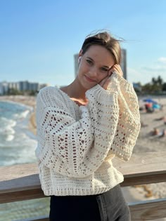 a woman is posing on the beach with her hand on her head and looking at the camera