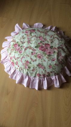 a pink and white flowered pillow sitting on top of a wooden floor